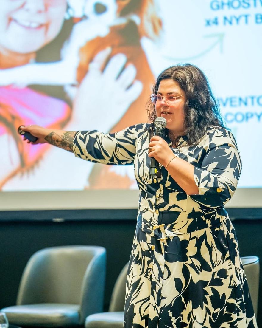 Crystal Adair-Benning speaking on stage with a microphone