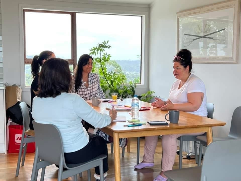 Crystal Adair-Benning coaching three writers around a table at a writing retreat