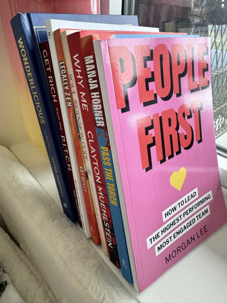 People First by Morgan Lee standing in front of the stack of client books