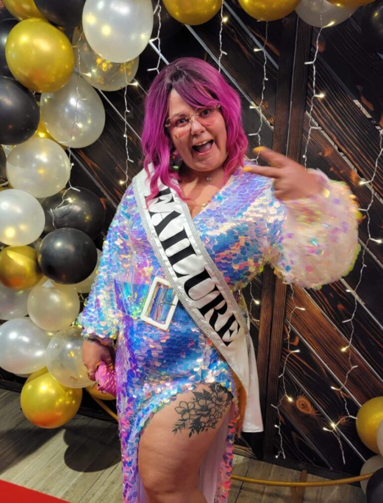 Crystal Adair-Benning in a sequin dress wearing a sash that says FAILURE