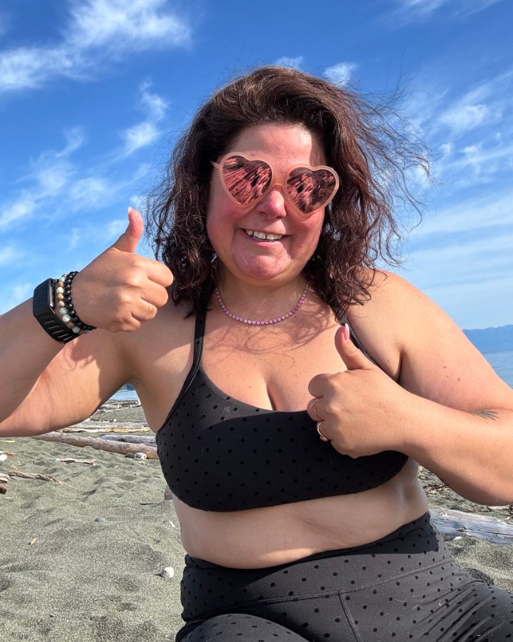 Crystal Adair-Benning on the beach in heart sunglasses giving 2 thumbs up
