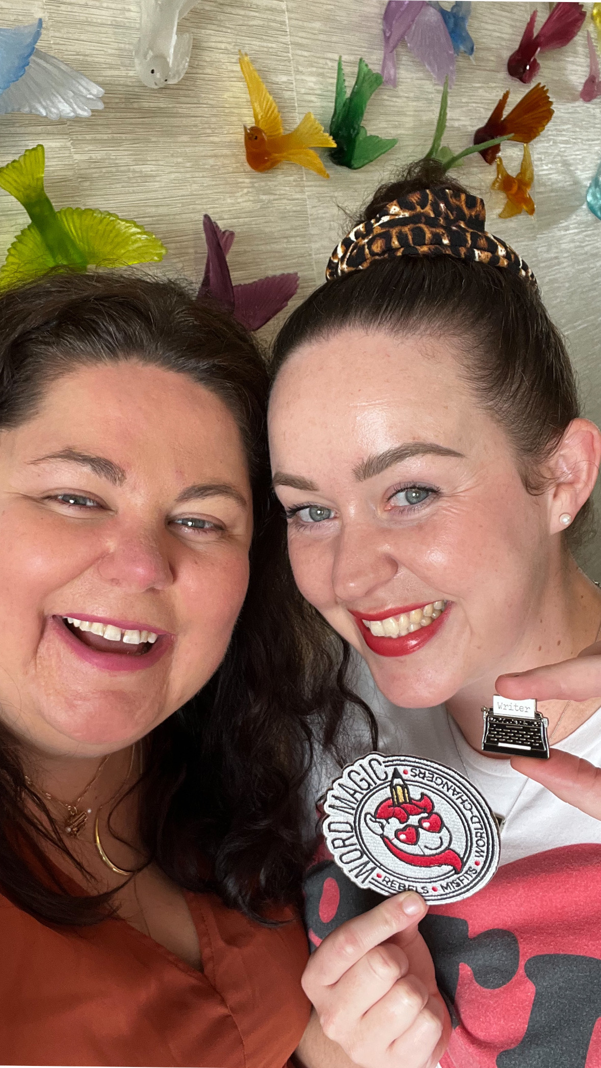Two writers holding a Word Magic patch and a typewriter pin