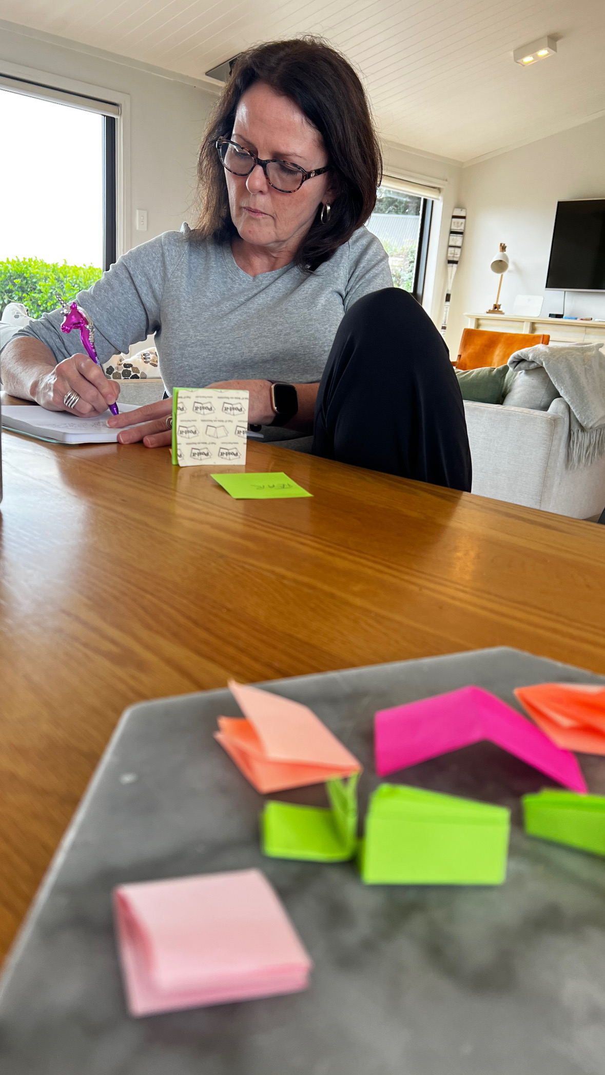 A writer making notes at a table covered in coloured sticky notes