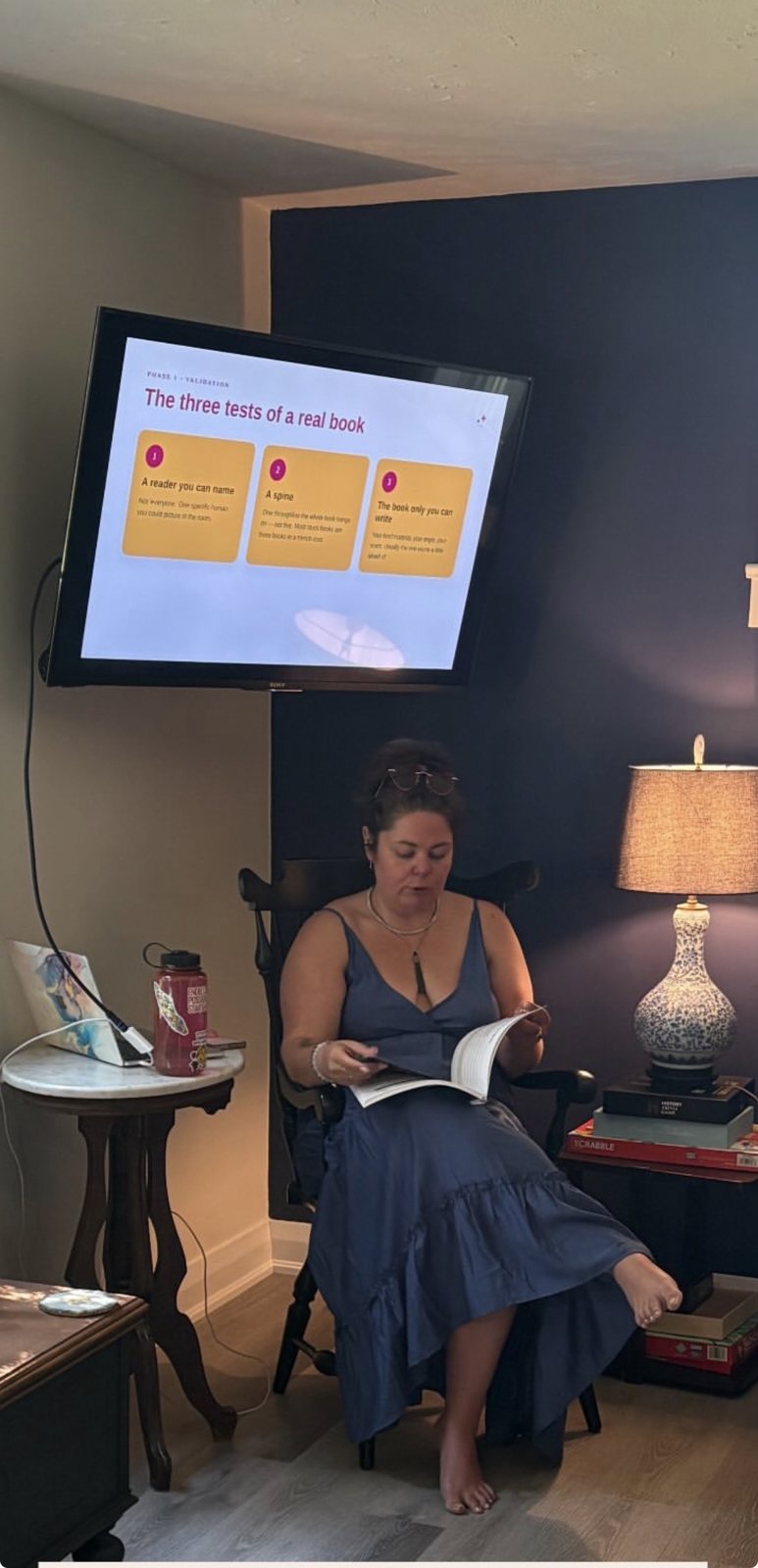 A writer reading beneath a screen showing The three tests of a real book at a Createcation in Niagara-on-the-Lake
